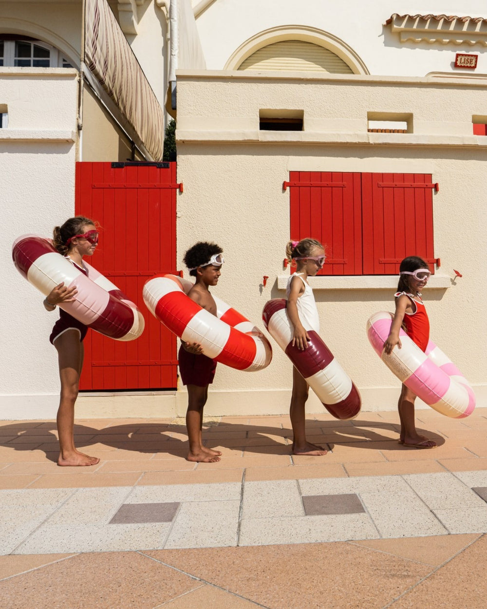 Kids carrying red and white striped swim rings