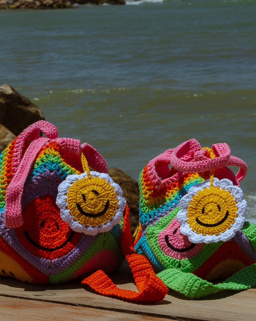 Colourful crochet bags with smiley faces by the sea